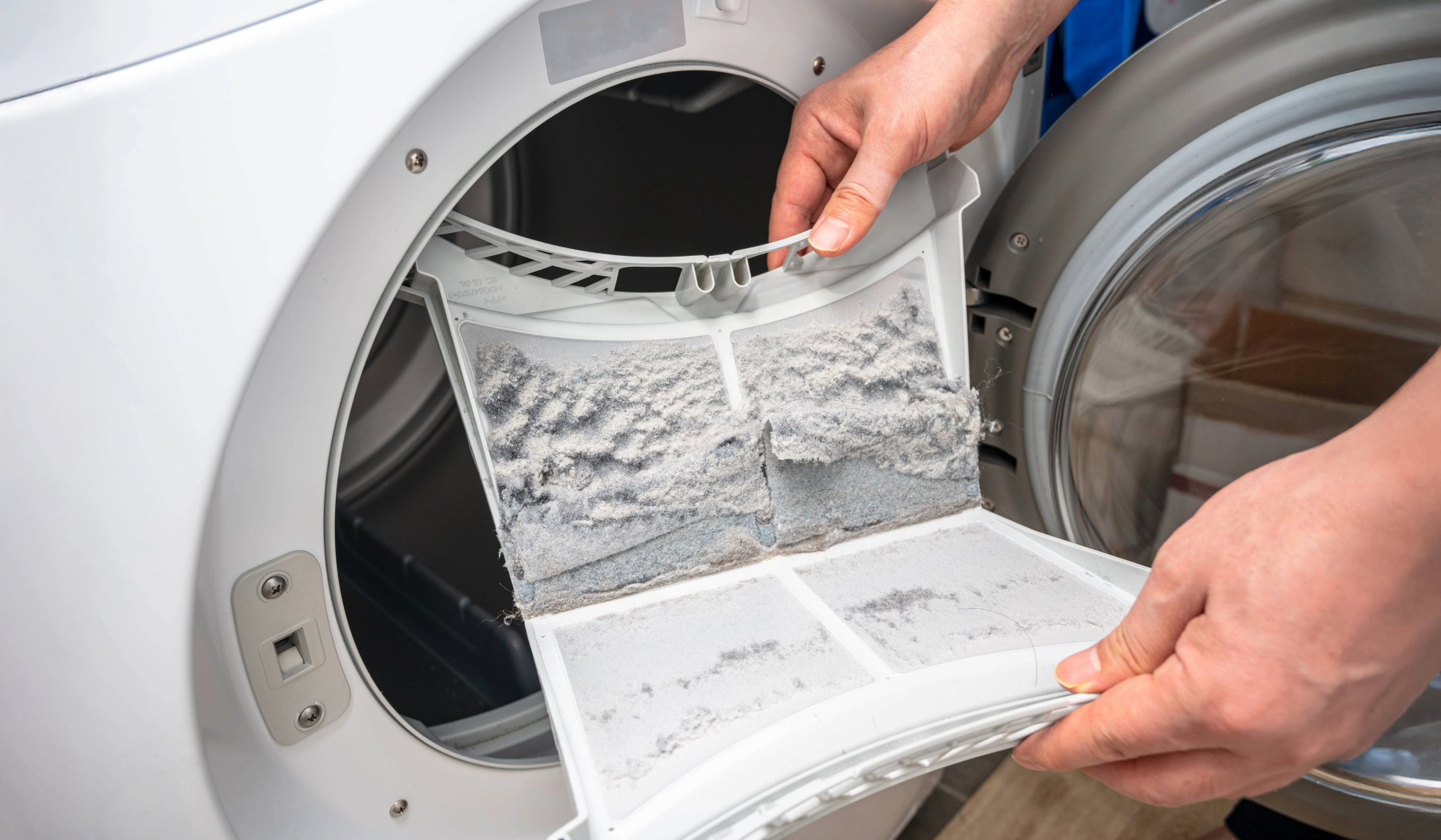 image showing a person holding a full open lint filter inside a dryer